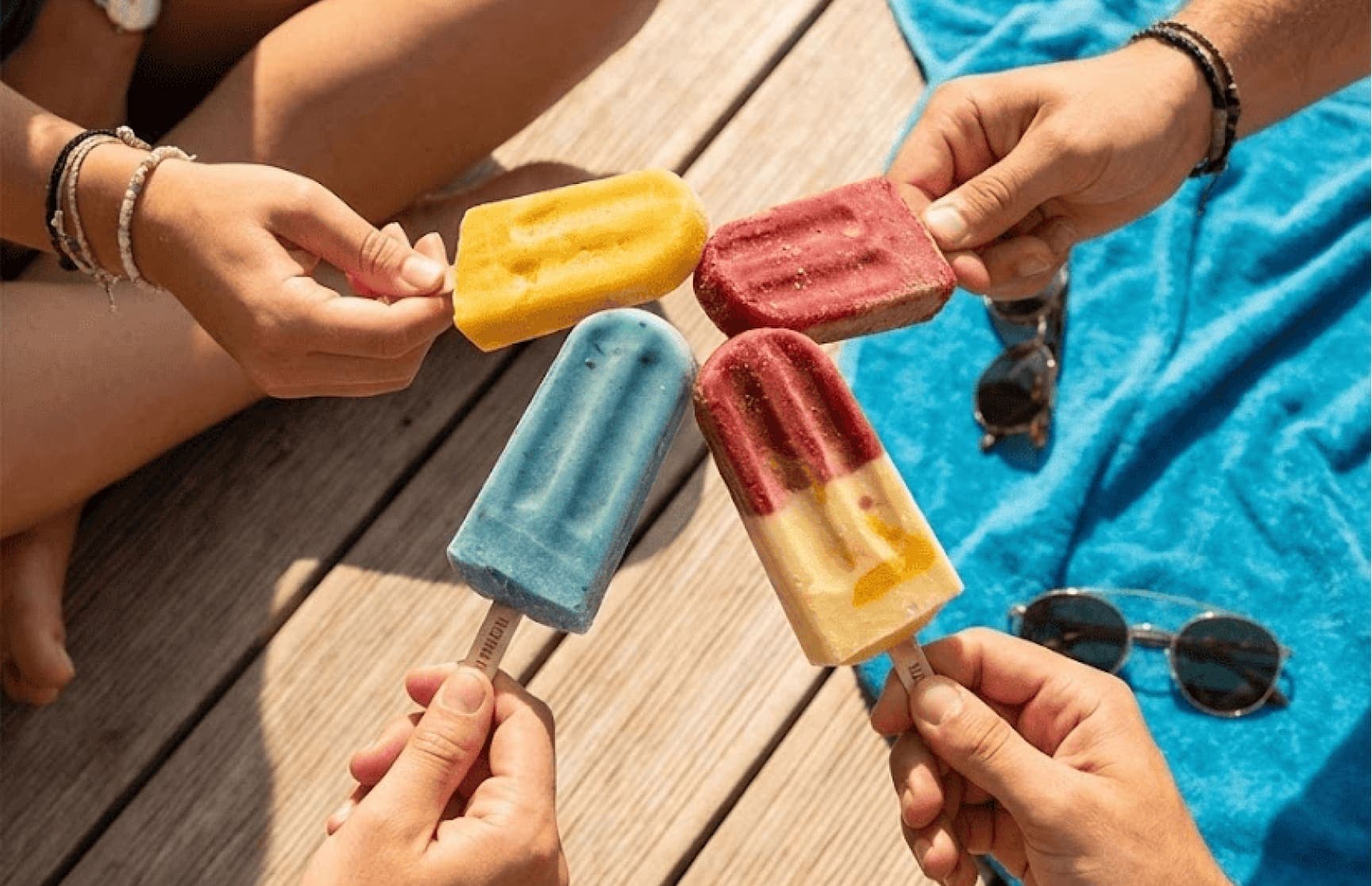 Friends sharing LA PALETA paletas at the beach